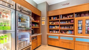 Una kitchenette equipada con refrigerador, microondas y despensa provista de botanas y bebidas.
