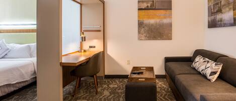 A hotel room with a bed, a desk, a sofa, and a coffee table.
