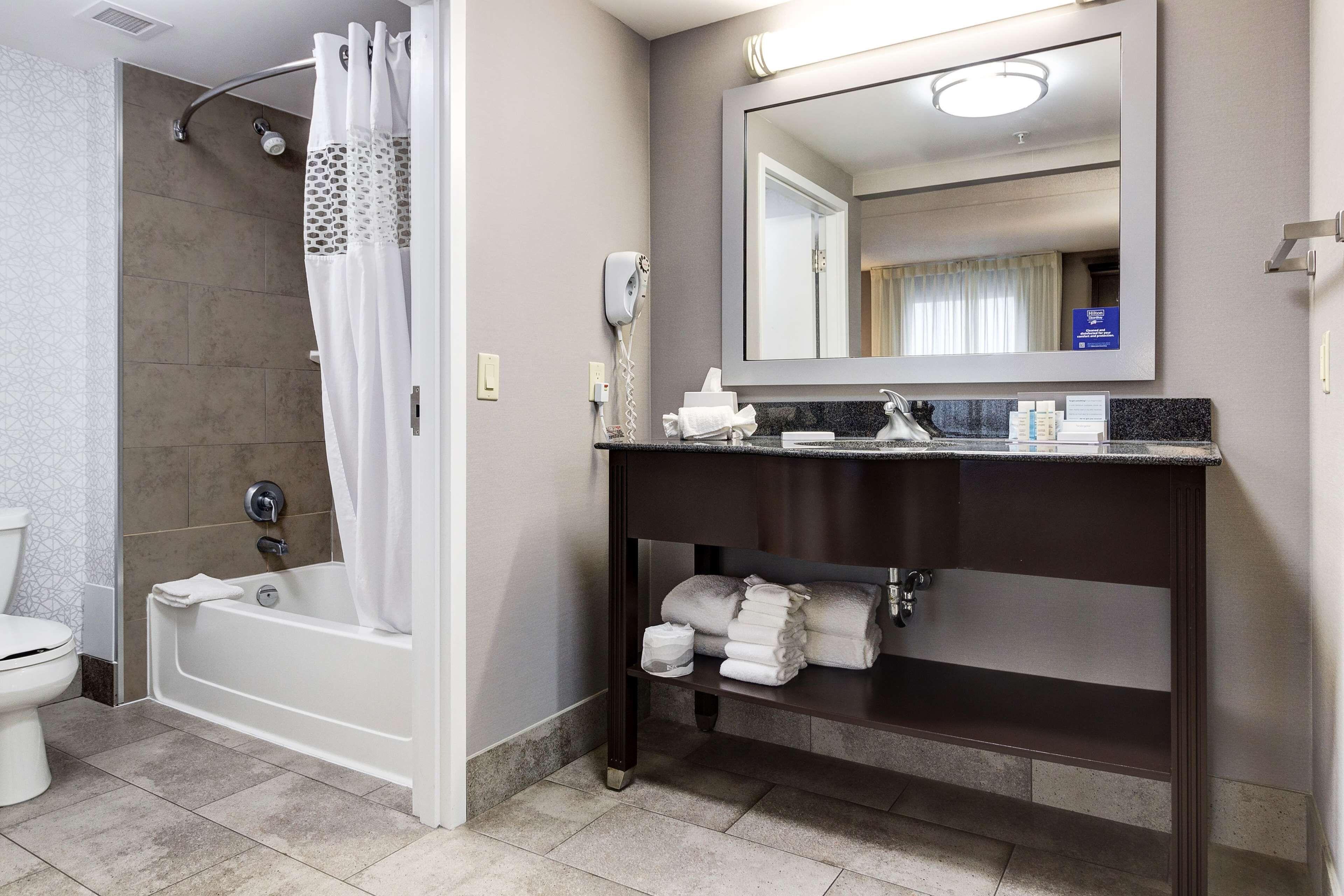 Un baño con bañera, inodoro, ducha, tocador con espejo y toallas.