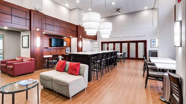 A spacious hotel lobby with a bar area, seating, and a television.