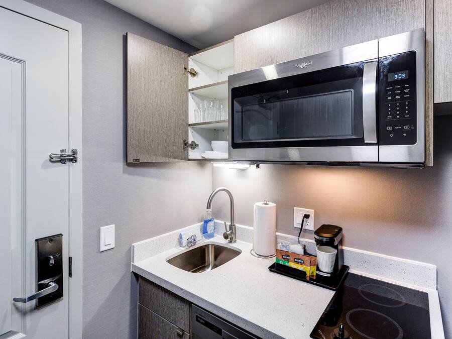 A modern kitchen with a built-in microwave, stainless steel sink, and a dishwasher.