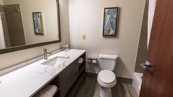 Une salle de bain moderne avec un lavabo en marbre, des toilettes et deux tableaux abstraits accrochés aux murs.