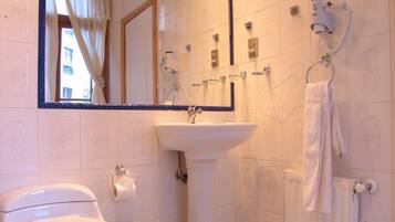 Un baño con inodoro, lavabo, espejo, toallero y radiador.