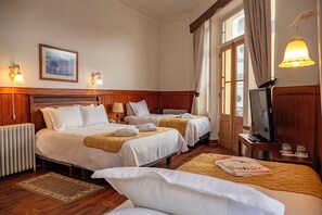 Habitación de hotel con dos camas, televisión y ventana con cortinas.