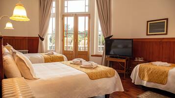 Habitación de hotel con dos camas, televisión y vistas al exterior.