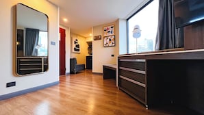 A hotel room with a wooden floor, a large mirror, a desk, a chair, a sofa, and artwork on the walls. - Holiday Inn Mexico City - Plaza Universidad by IHG (Mexico City)