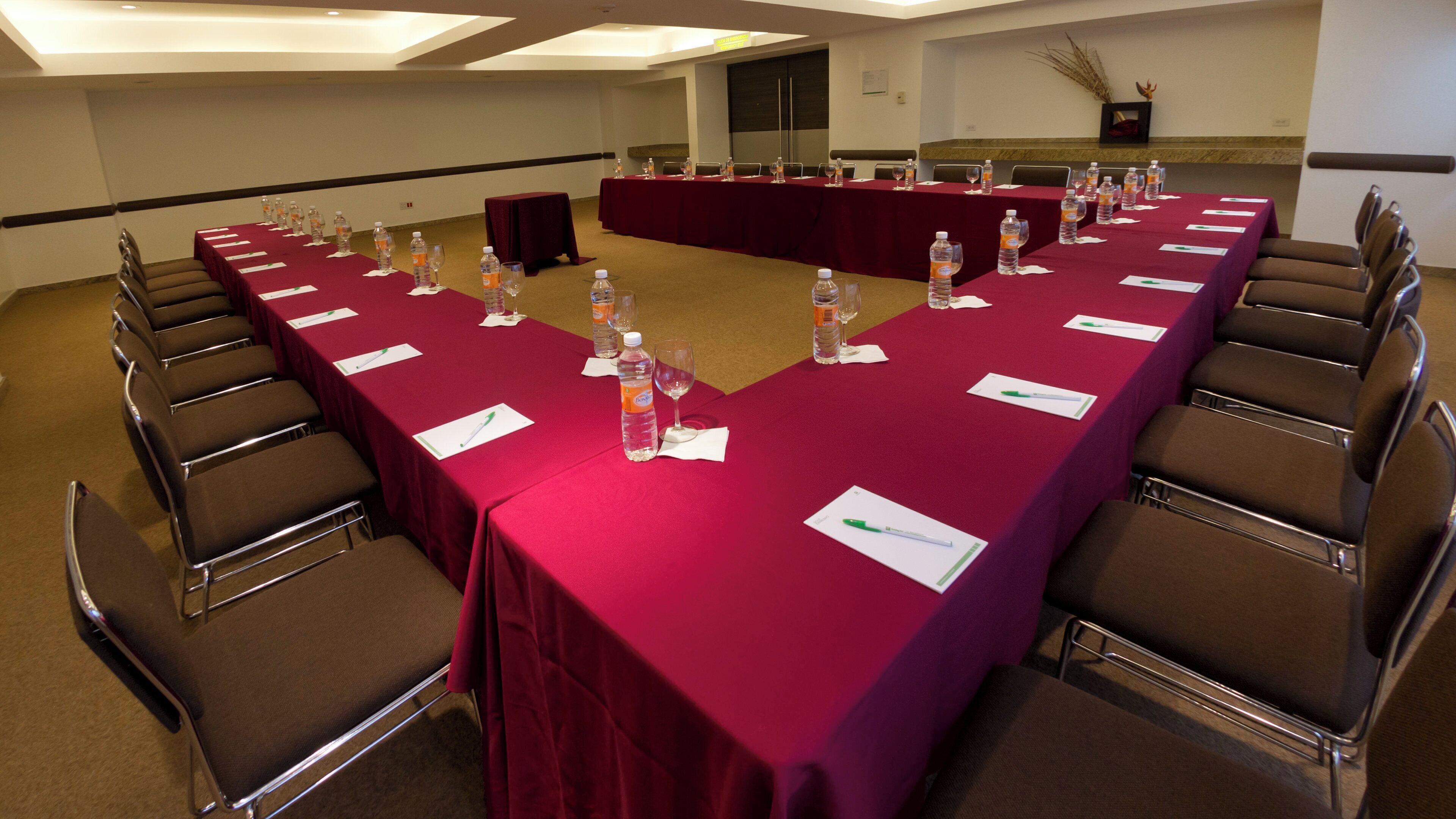 A conference room with a long table, chairs, water bottles, and documents.