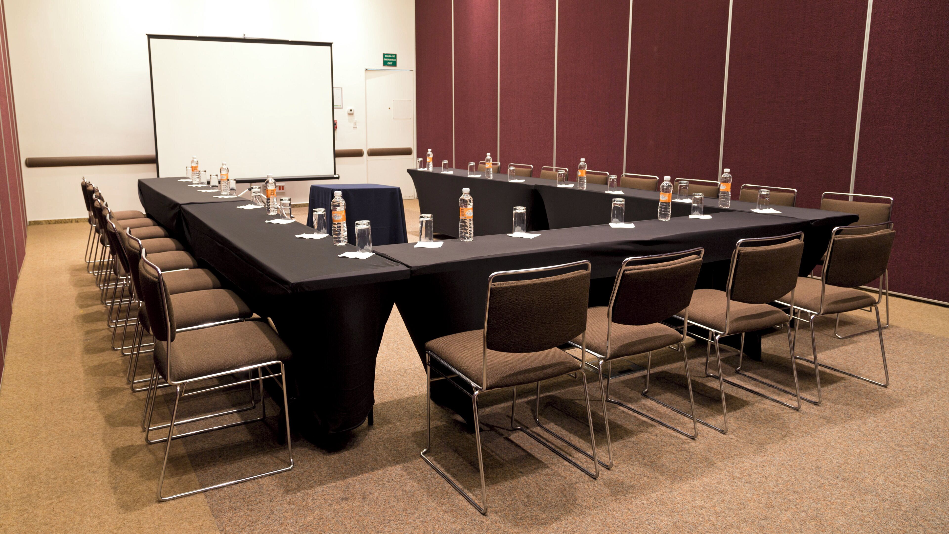 A conference room with a long table, chairs, water bottles, and a whiteboard.