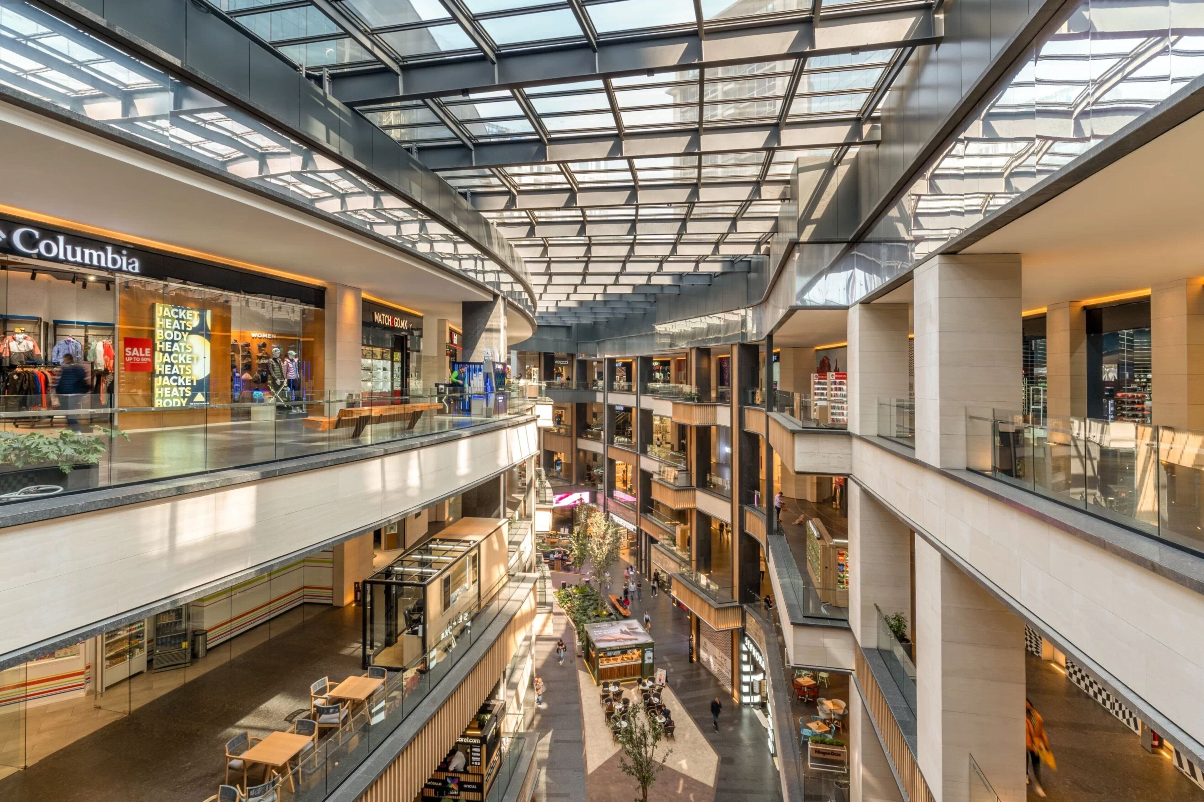 Een meerlaags winkelcentrum met glazen balustrades, diverse winkels en zitgedeeltes.
