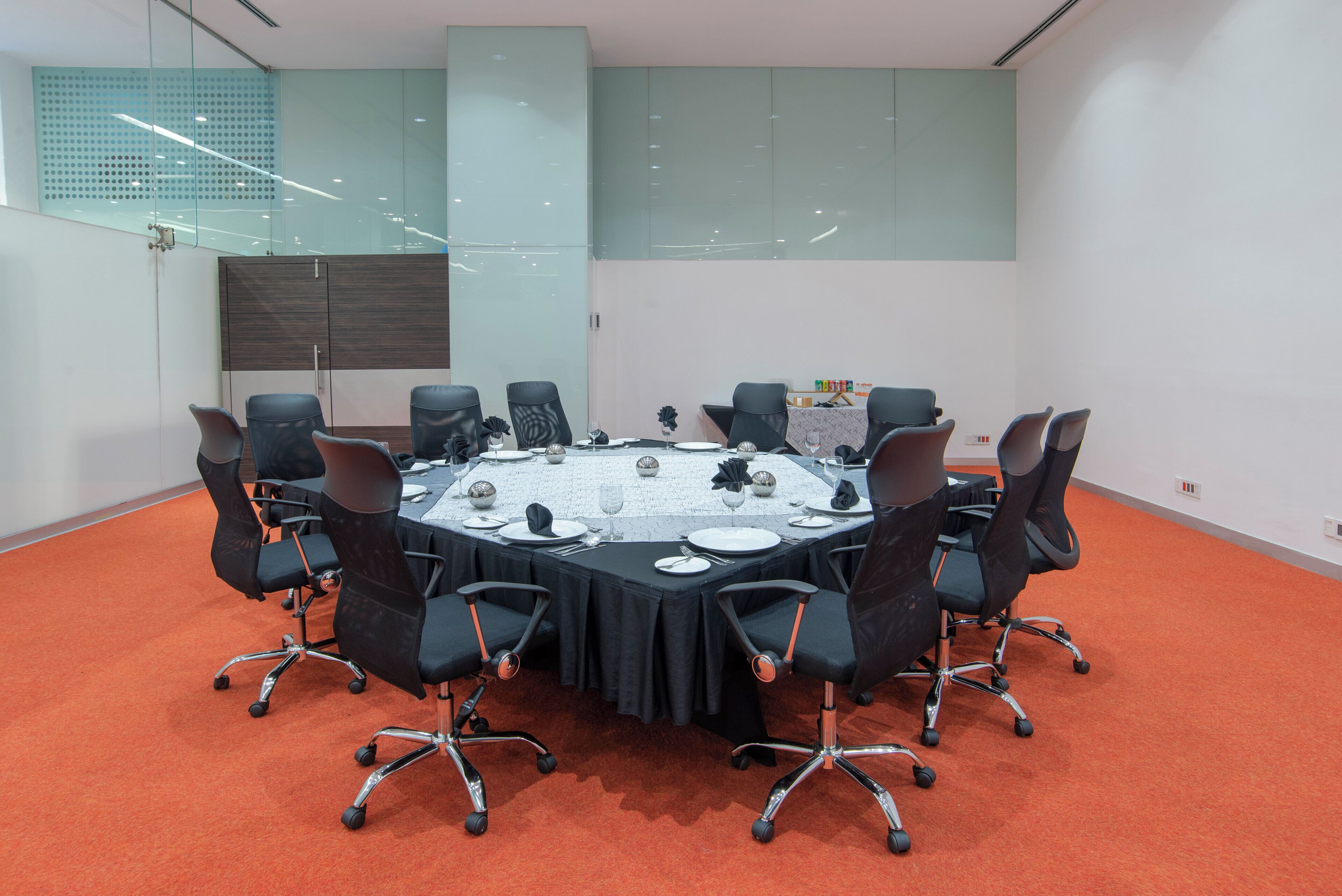 A conference room with a round table, black chairs, and a red carpet.