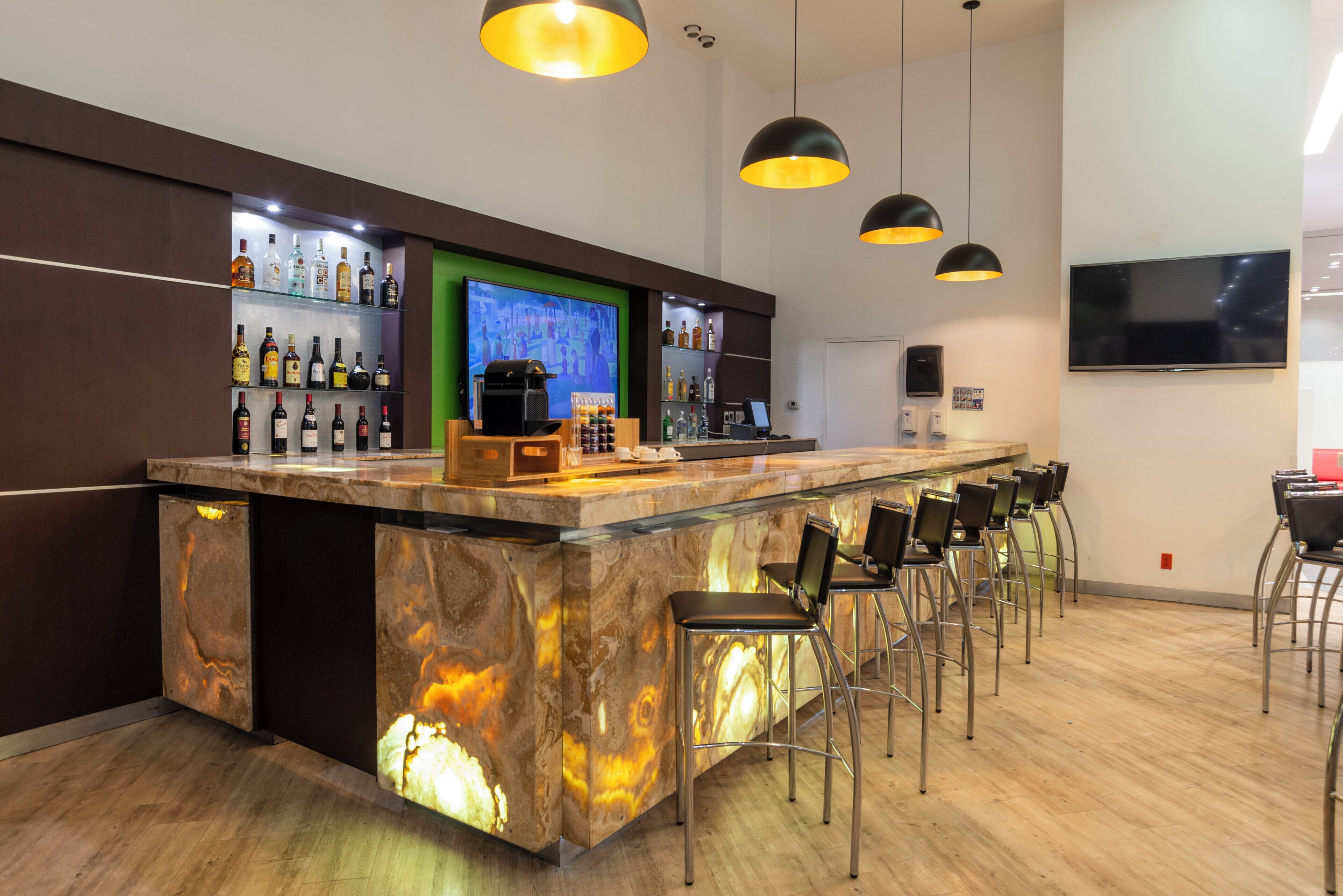 A bar area with a marble countertop, bar stools, and overhead pendant lighting.