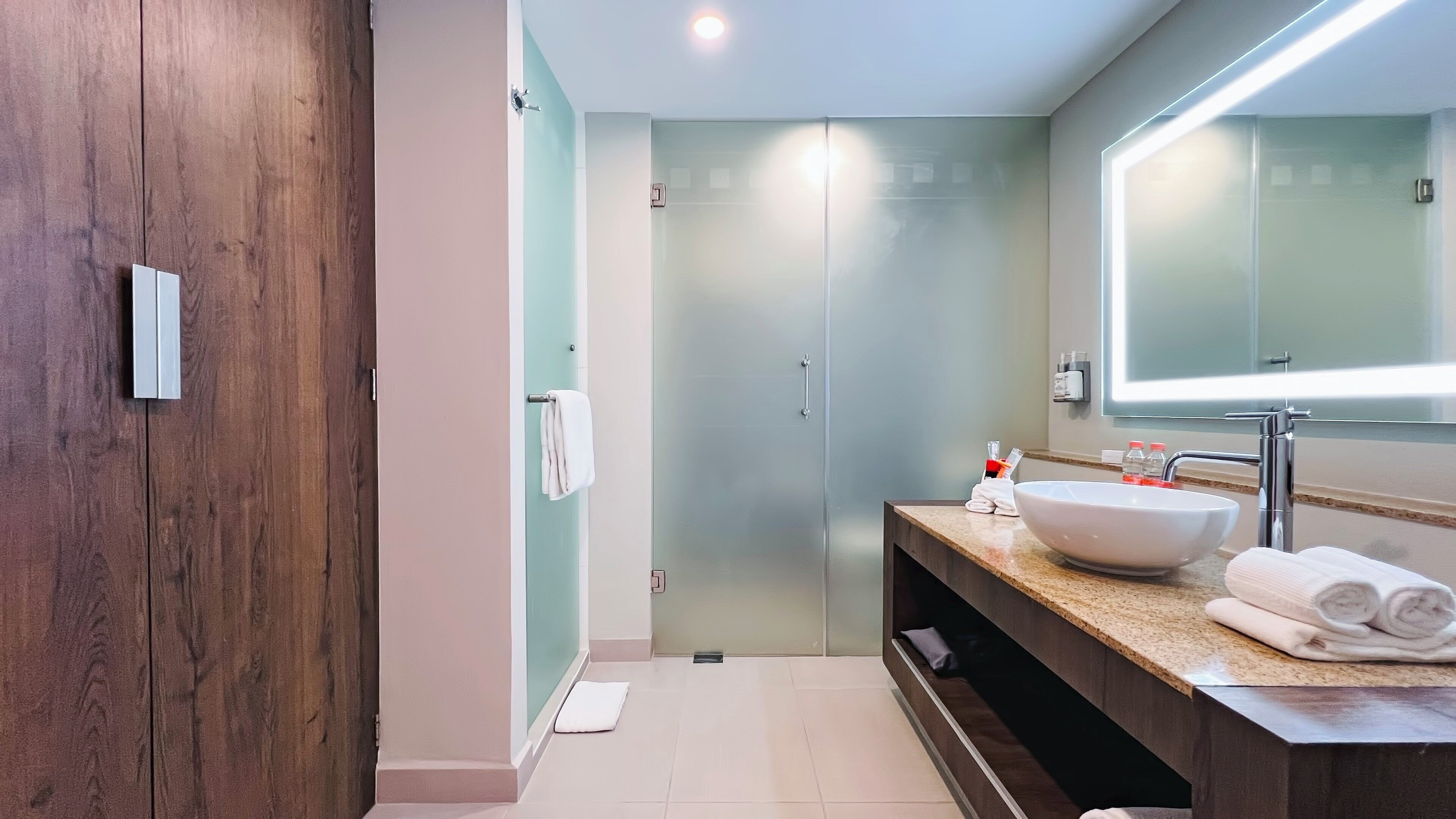 Un baño moderno con un espejo grande, un lavabo blanco y un mueble de tocador de madera.