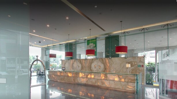 A modern lobby with a marble reception desk, glass walls, and red pendant lighting. - Holiday Inn Mexico City - Plaza Universidad by IHG (Mexico City)