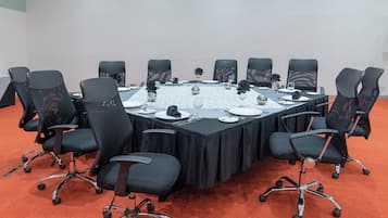 Ein Konferenzraum mit rundem Tisch, schwarzen Stühlen und einer weißen Tischdecke.