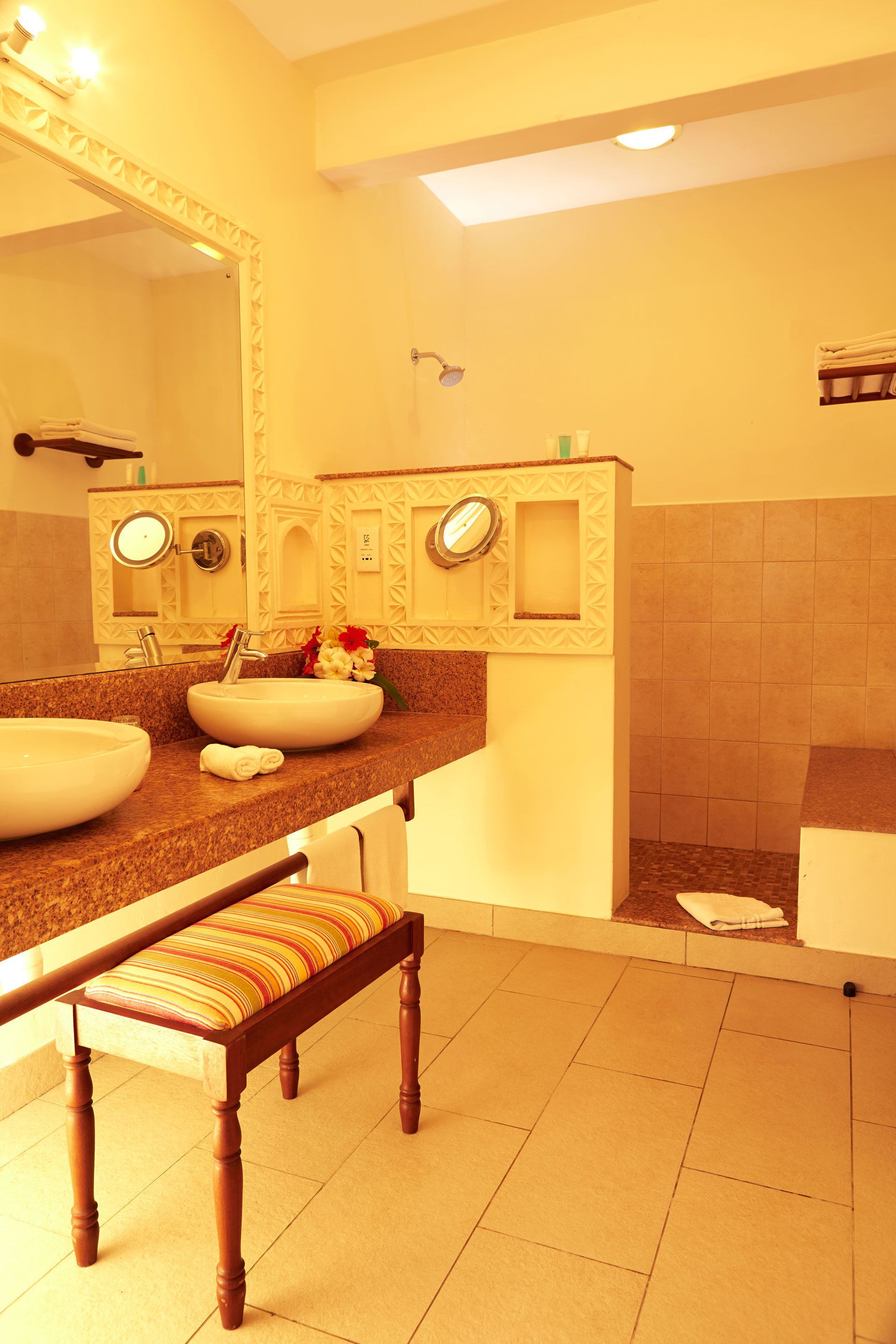 Un baño con dos lavamanos, un espejo grande y un banco.