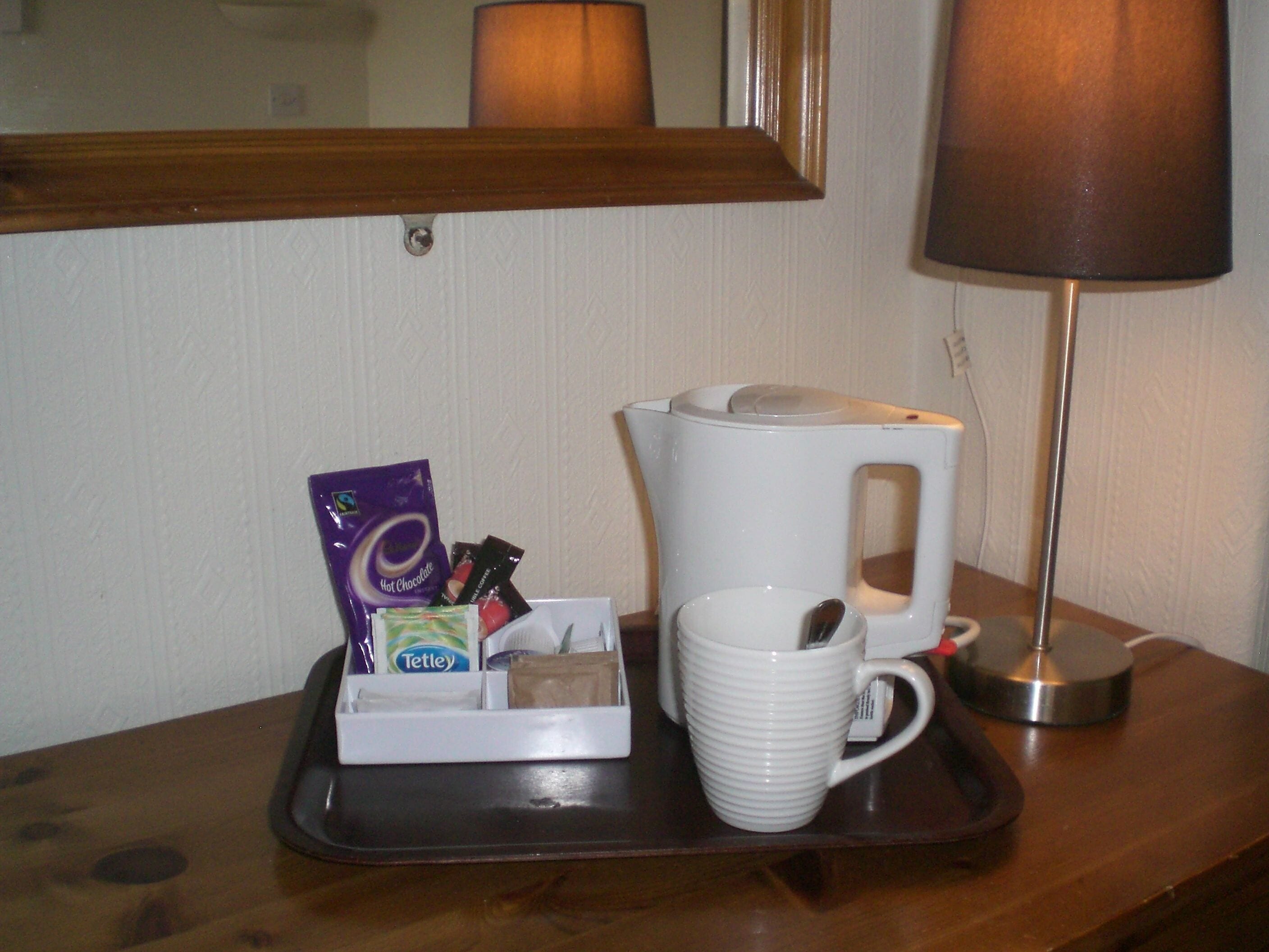 A tray with a coffee maker, a mug, and a packet of hot chocolate.