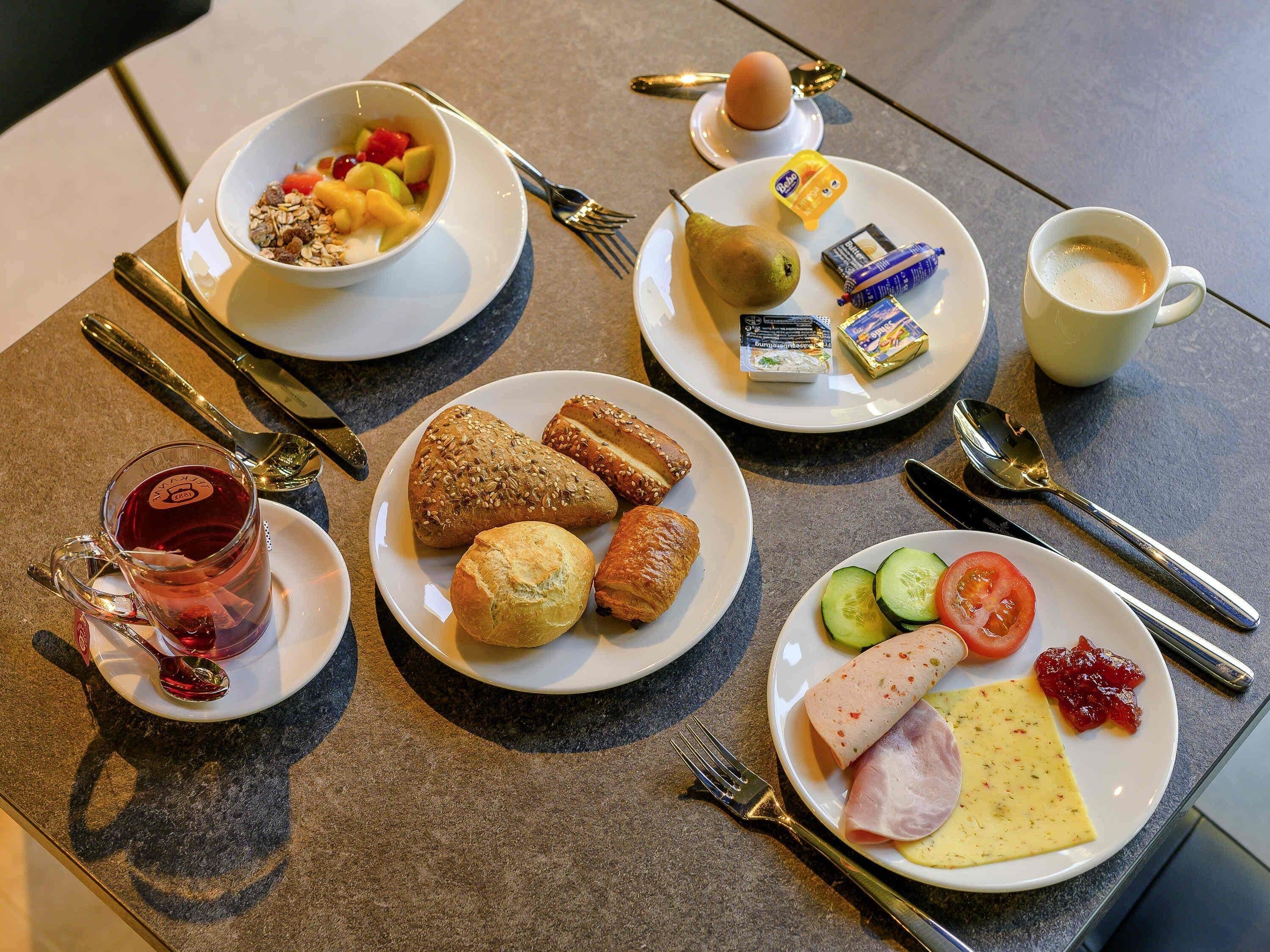 A breakfast setting with plates of food, a cup of coffee, and cutlery.