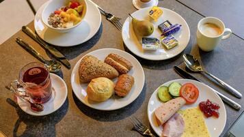 A breakfast setting with plates of food, a cup of coffee, and cutlery.