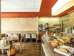 Ein Frühstücksbuffet mit verschiedenen Speisen, einer Kaffeemaschine und Sitzgelegenheiten.