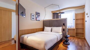 Quarto de hotel moderno com uma cama grande, mesa de cabeceira, luminária e prateleira embutida.