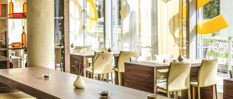 A modern dining area with a long wooden table, chairs, and a large window with curtains.