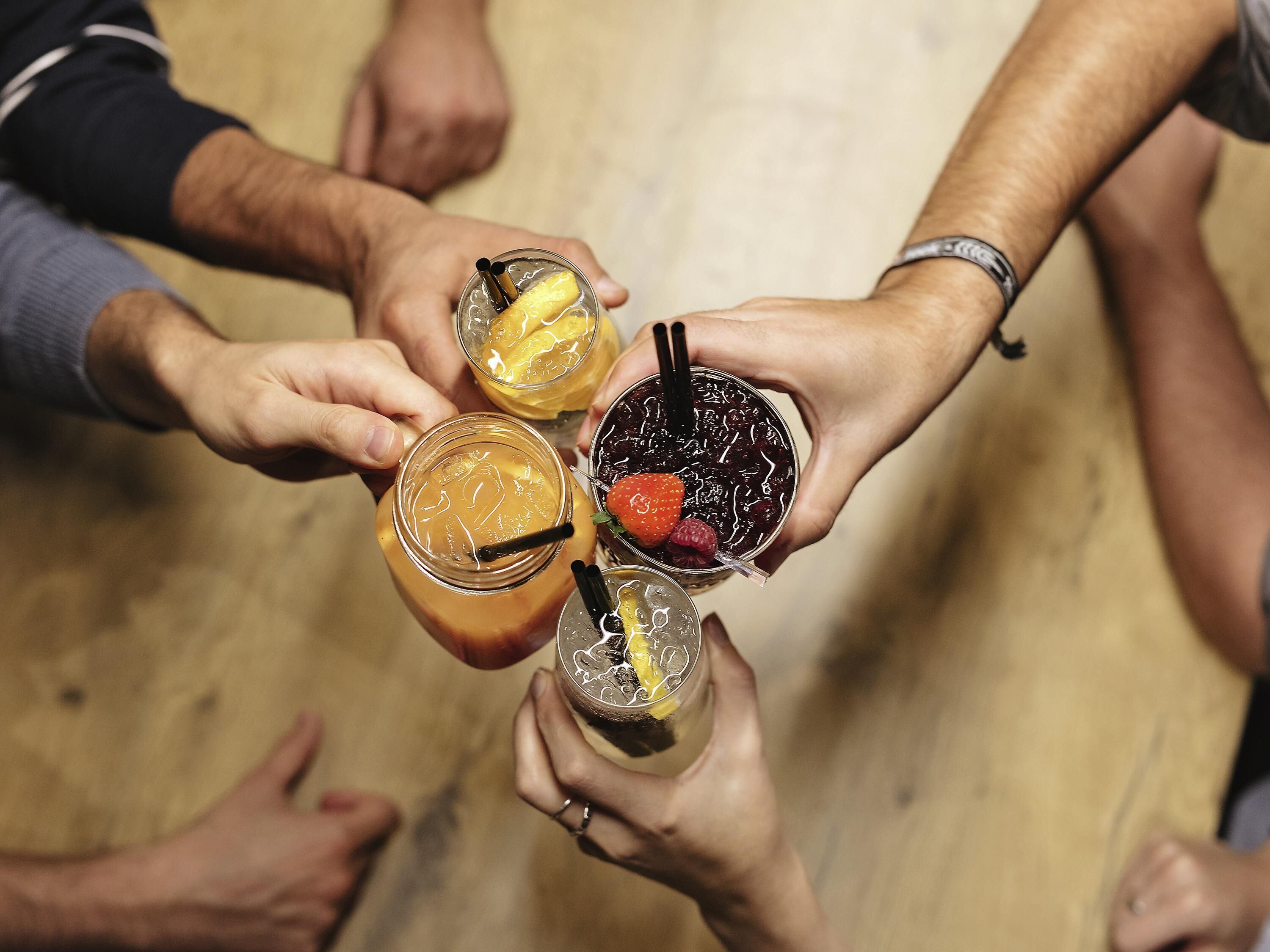 A group of people holding four different drinks, each with unique garnishes.