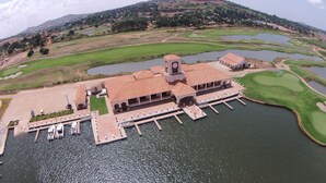 An aerial view of a resort with a central building, multiple docks, and surrounding water bodies. - Lake Victoria Serena Golf Resort & Spa (Kampala)