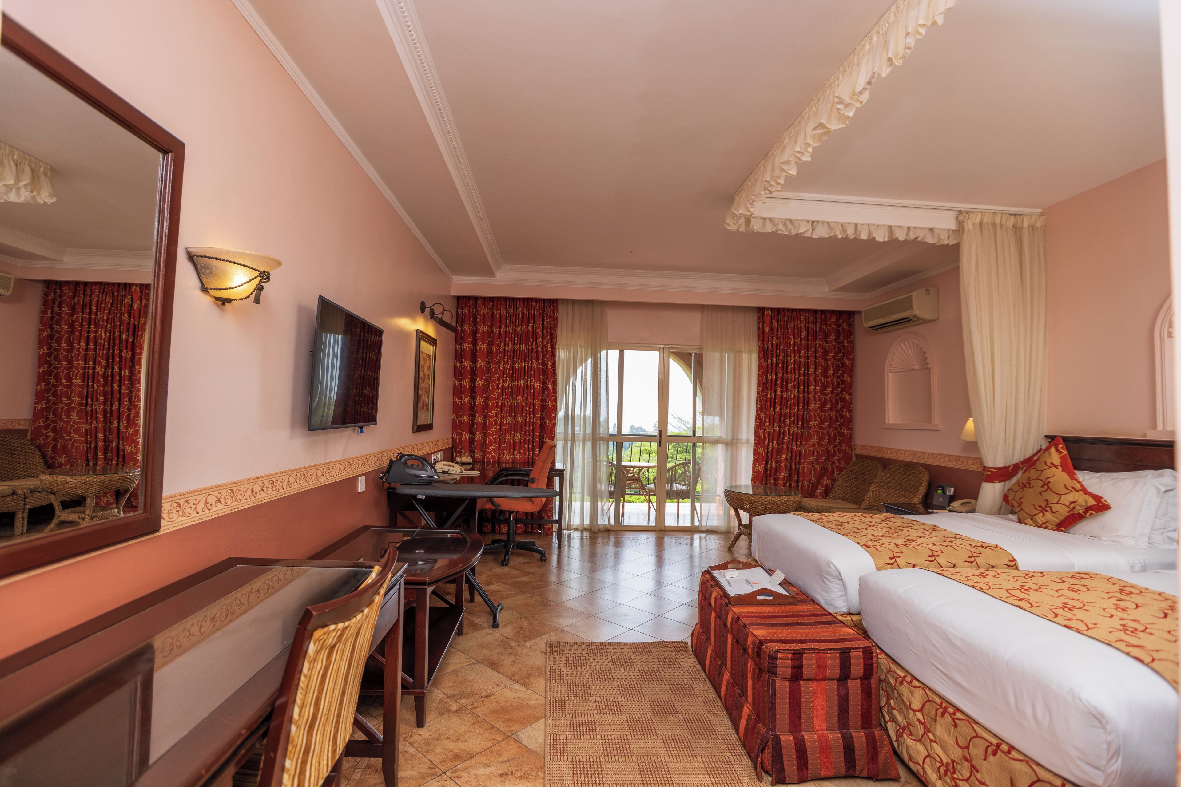 Ein Hotelzimmer mit einem Bett, einem Schreibtisch, einem Sessel, einem Fernseher und Blick ins Freie.