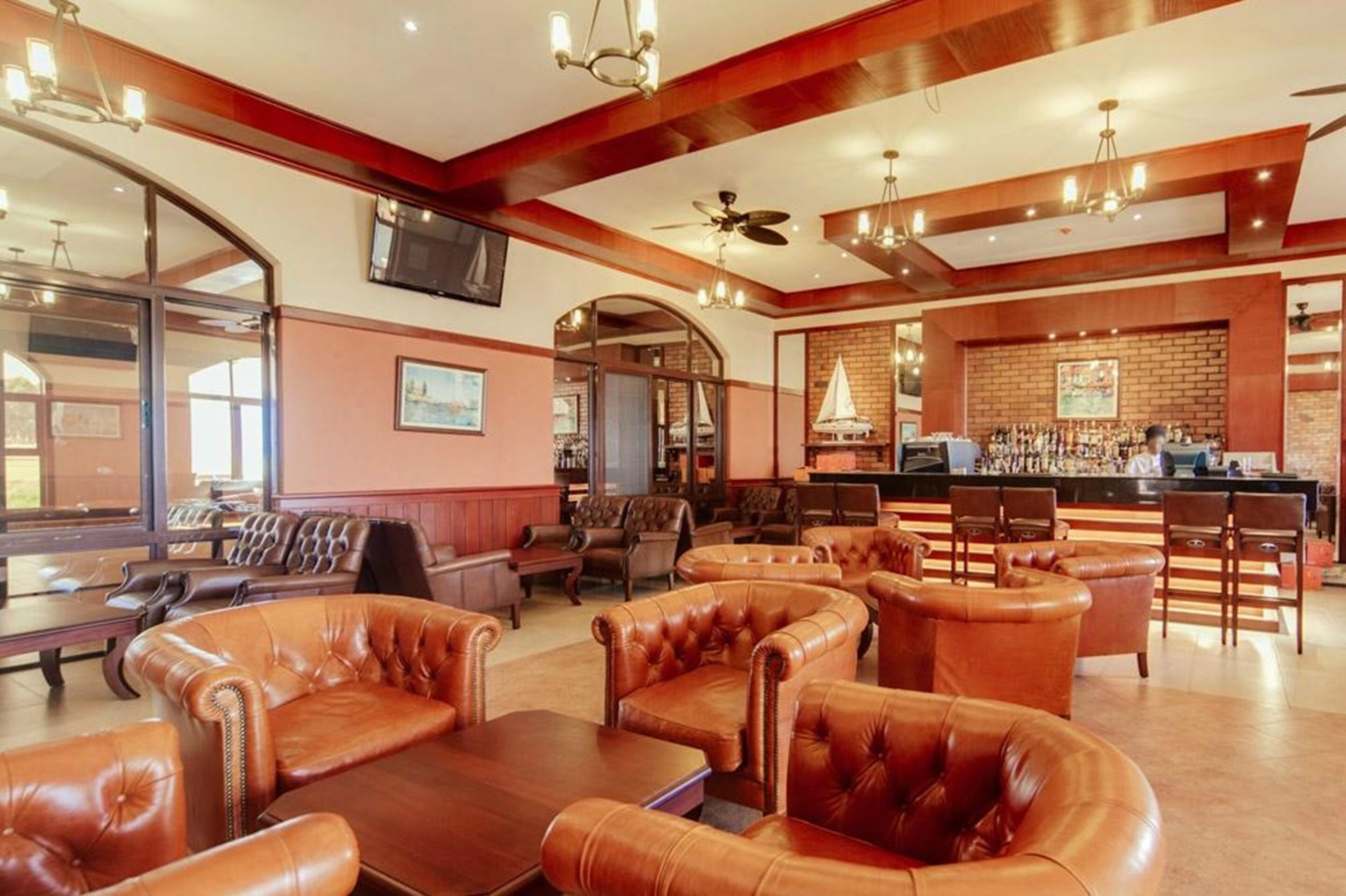 A bar area with leather seating, a bar counter, and a television mounted on the wall.