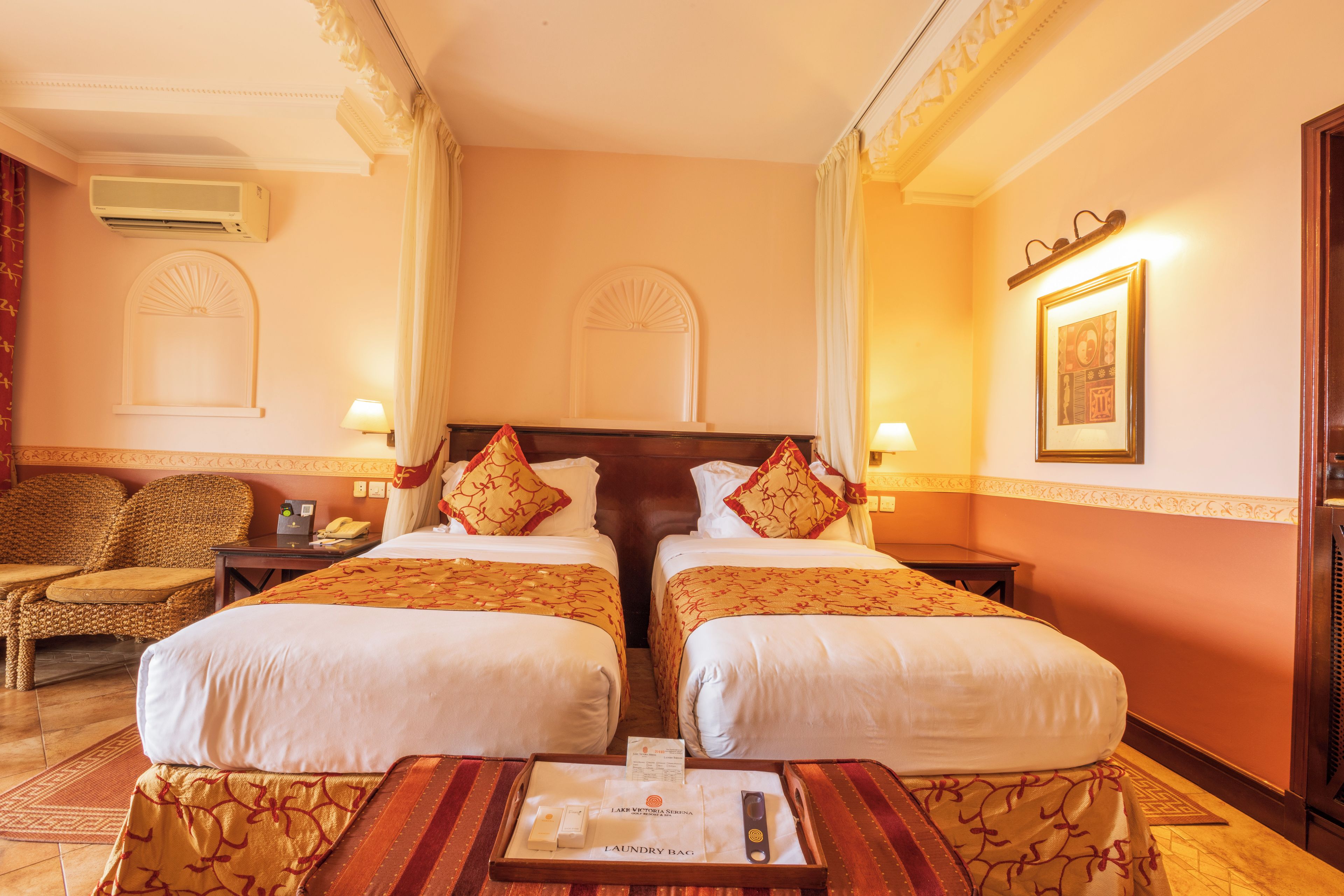 A hotel room with two beds, a sitting area, and a desk.