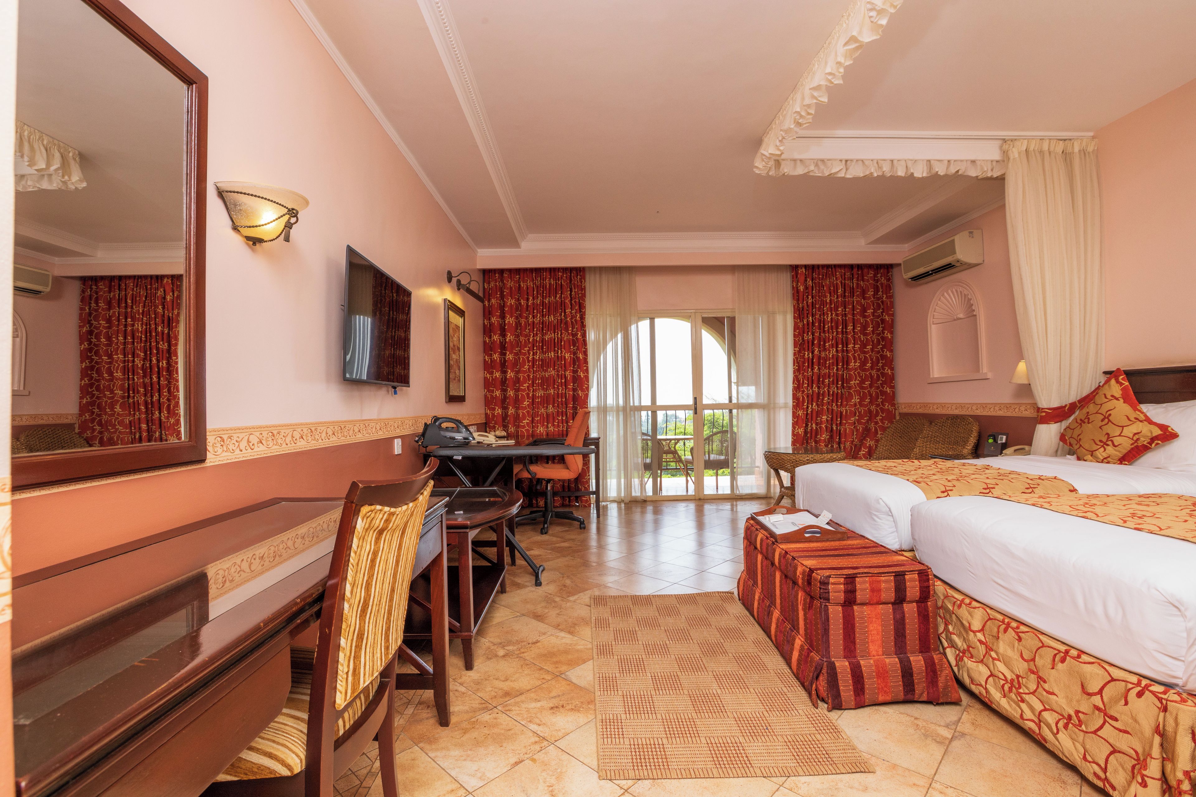 A hotel room with a bed, a desk, a chair, a television, and a large window.