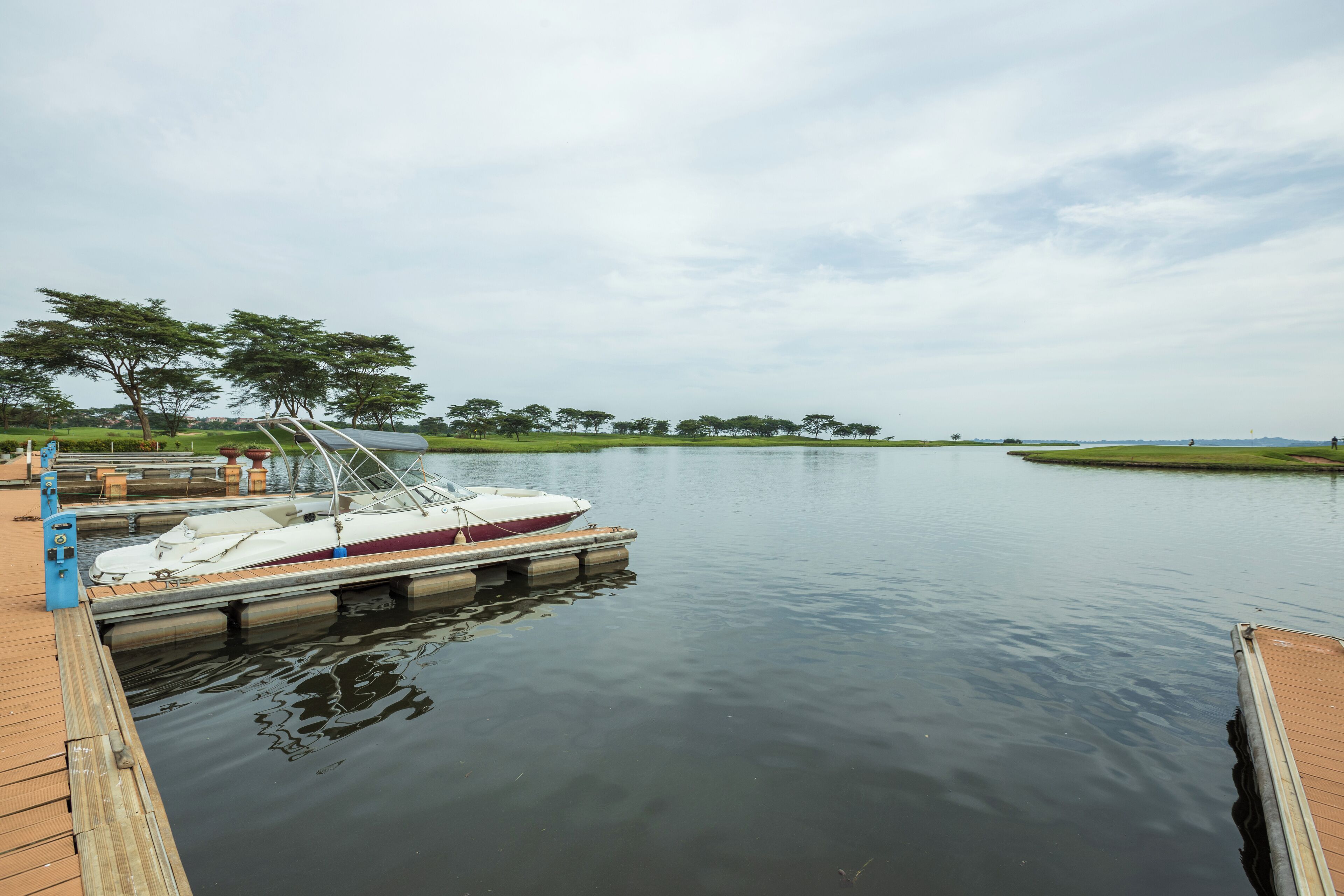 A calm lake with a dock and a boat.