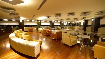 Un'ampia hall con un divano curvo, diverse poltrone e una ringhiera in vetro.