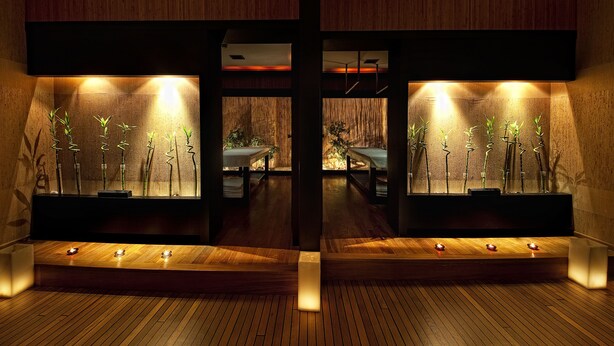 Un área de spa con suelo de madera, un mostrador de recepción y un espacio de recepción con escritorio y sillas.