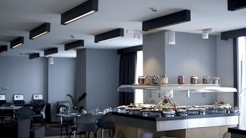 A modern hotel dining area with a buffet setup, including various food items and condiments.