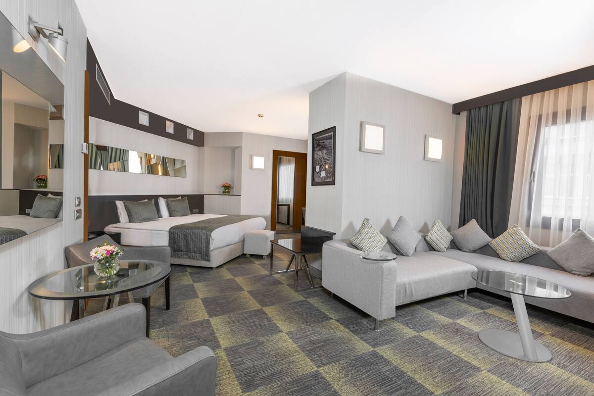 A modern hotel room with a sofa, a bed, a small table, and a mirror.