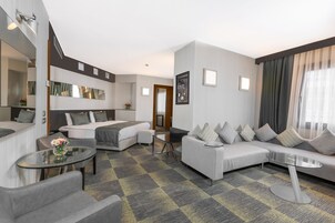 A modern hotel room with a sofa, a bed, a small table, and a mirror.