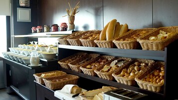 A buffet with various breads and pastries displayed in wicker baskets.