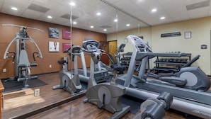Un gimnasio con diversos equipos de ejercicio, incluyendo cintas de correr, elípticas y máquinas de pesas.