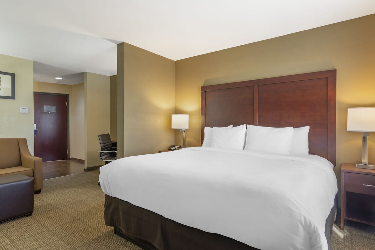 Une chambre d’hôtel avec un grand lit, une chaise, un bureau et une lampe.