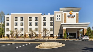 Un hotel con diseño moderno, que cuenta con una entrada central, varios pisos y un estacionamiento.