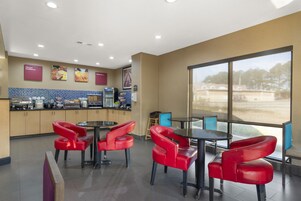 Un restaurante moderno con sillas rojas, un ventanal grande y un salpicadero de azulejos.