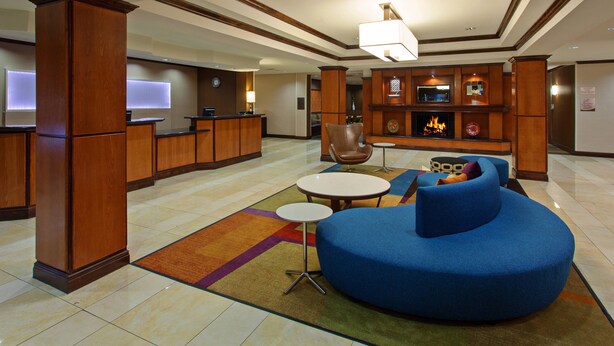 A hotel lobby with a reception desk, a fireplace, a blue sofa, and a coffee table. - Fairfield Inn & Suites by Marriott El Paso (El Paso)