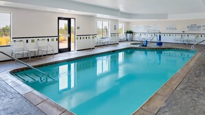 An indoor swimming pool with clear water, surrounded by white chairs and safety signs. - Fairfield Inn & Suites by Marriott El Paso (El Paso)