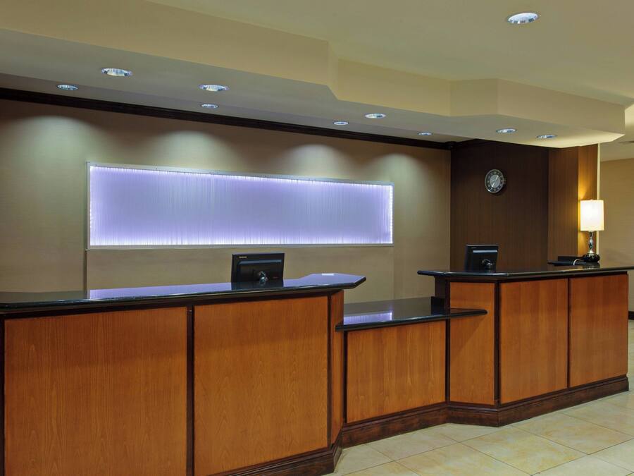 A reception desk with a built-in computer, a clock, and a lamp on the wall.