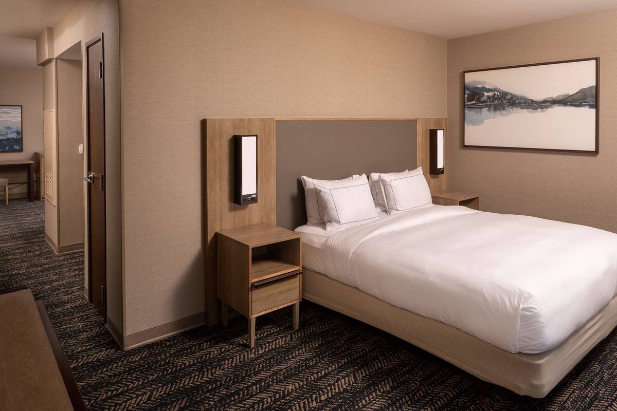 Une chambre d’hôtel avec un lit, une table de chevet, un bureau et une chaise.
