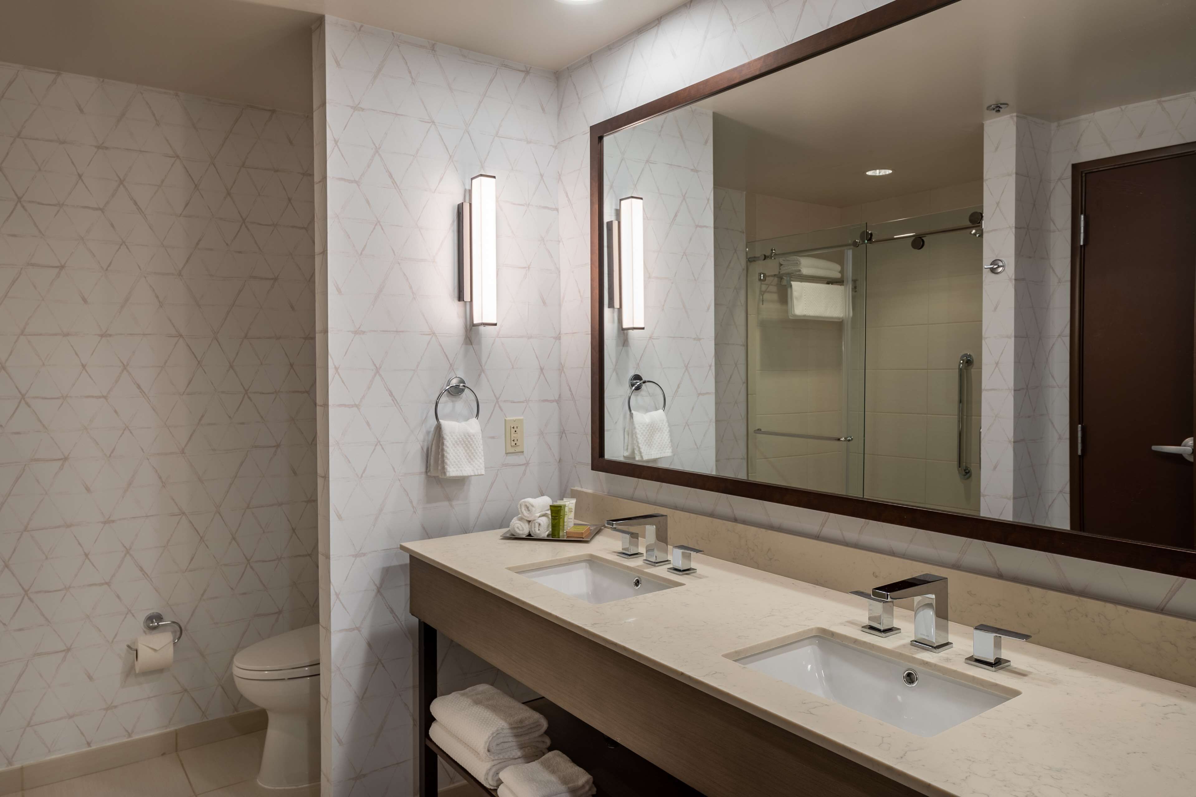 Un baño moderno con dos lavamanos, un espejo grande y una zona de ducha.