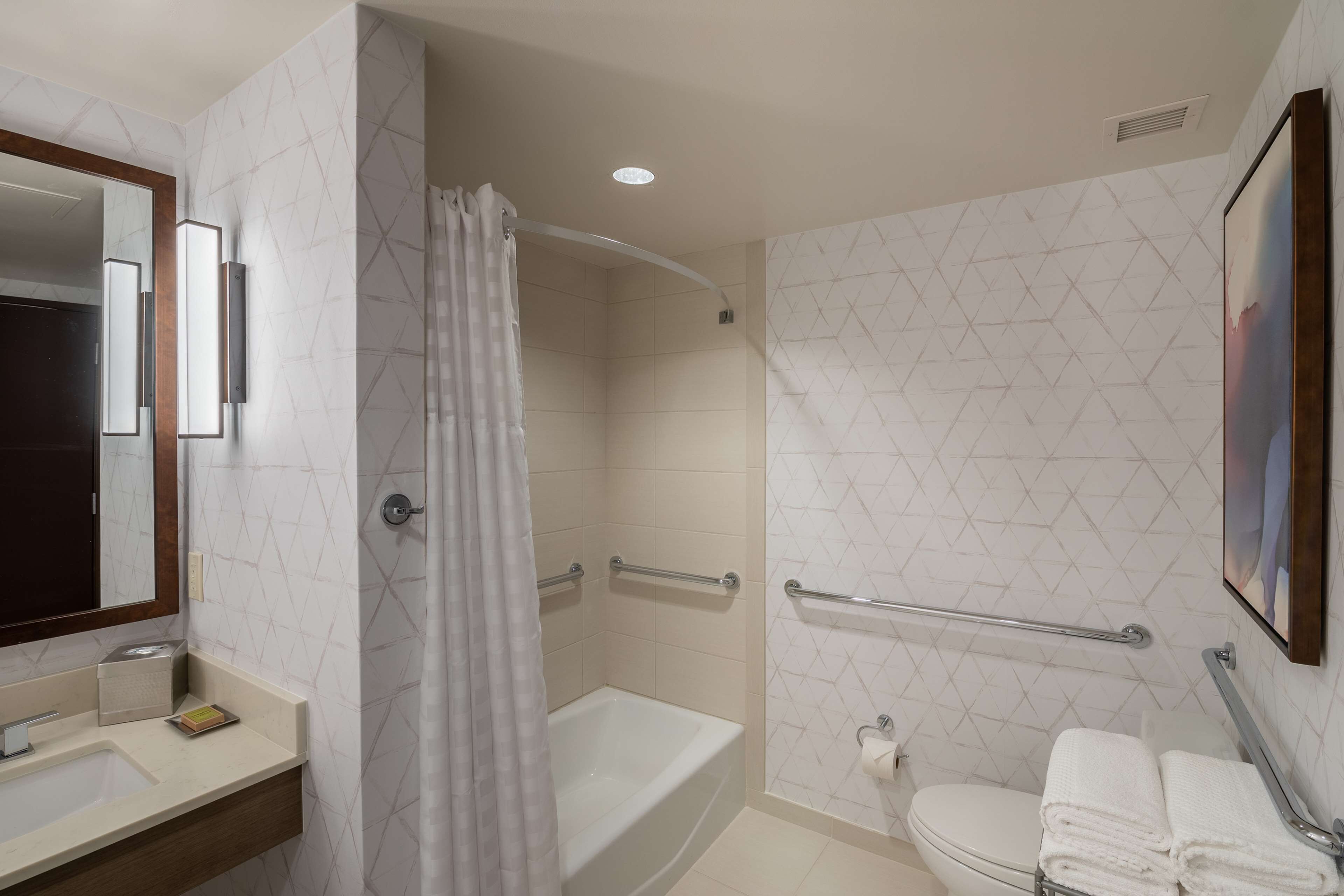 A modern bathroom with a bathtub, toilet, and shower area.