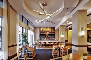 A hotel lobby with a bar area, seating arrangements, and a large window providing natural light. - Hilton Asheville Biltmore Park (Asheville)
