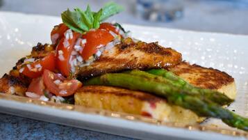 A plate of grilled chicken, asparagus, and tomatoes on a white plate.